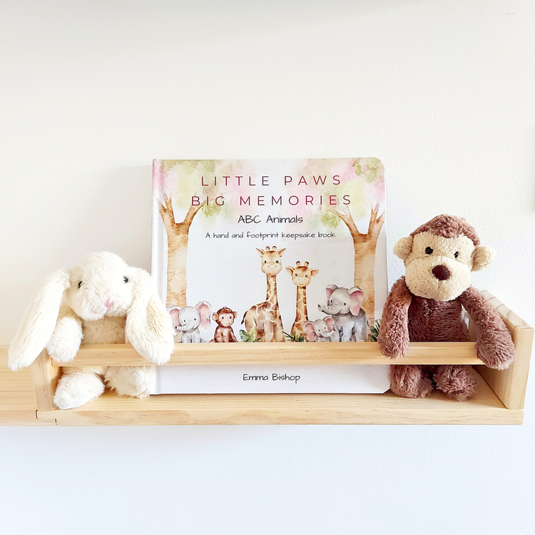 Little Paws Big Memories ABC Animals baby hand and footprint memory book displayed on nursery shelf with soft toys by Tiny Tiptoes