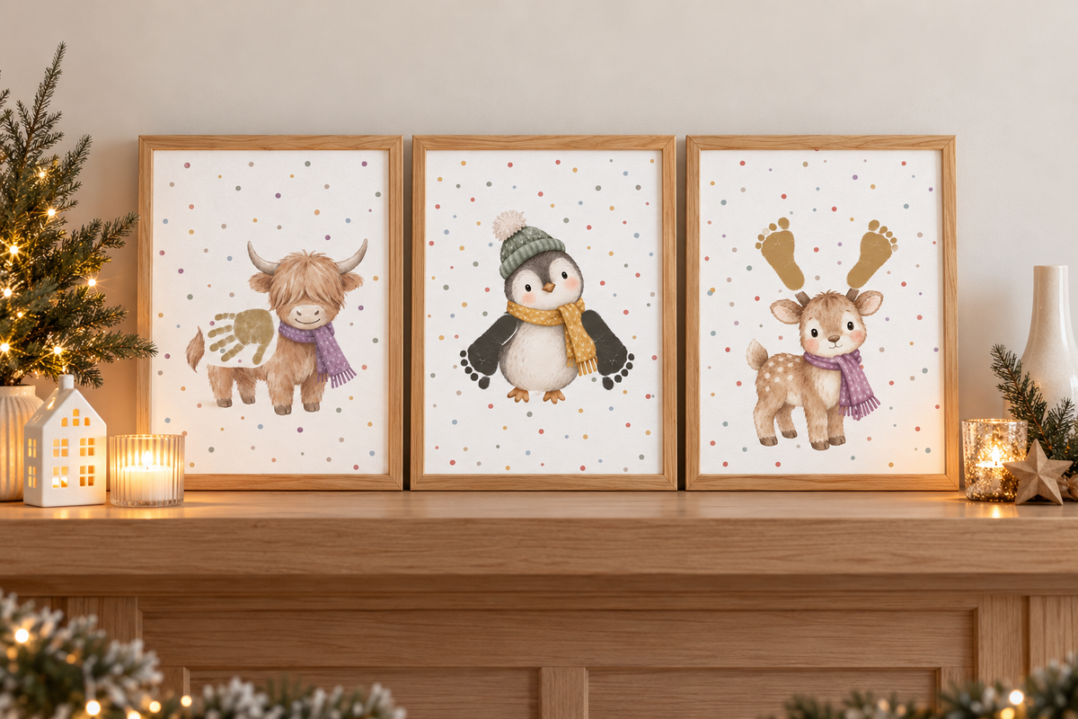Three framed christmas prints displayed on a wooden mantel. The prints feature a Highland cow with a handprint body, a penguin wearing a green beanie and yellow scarf with footprint wings, and a deer with foot print antlers and a purple scarf.