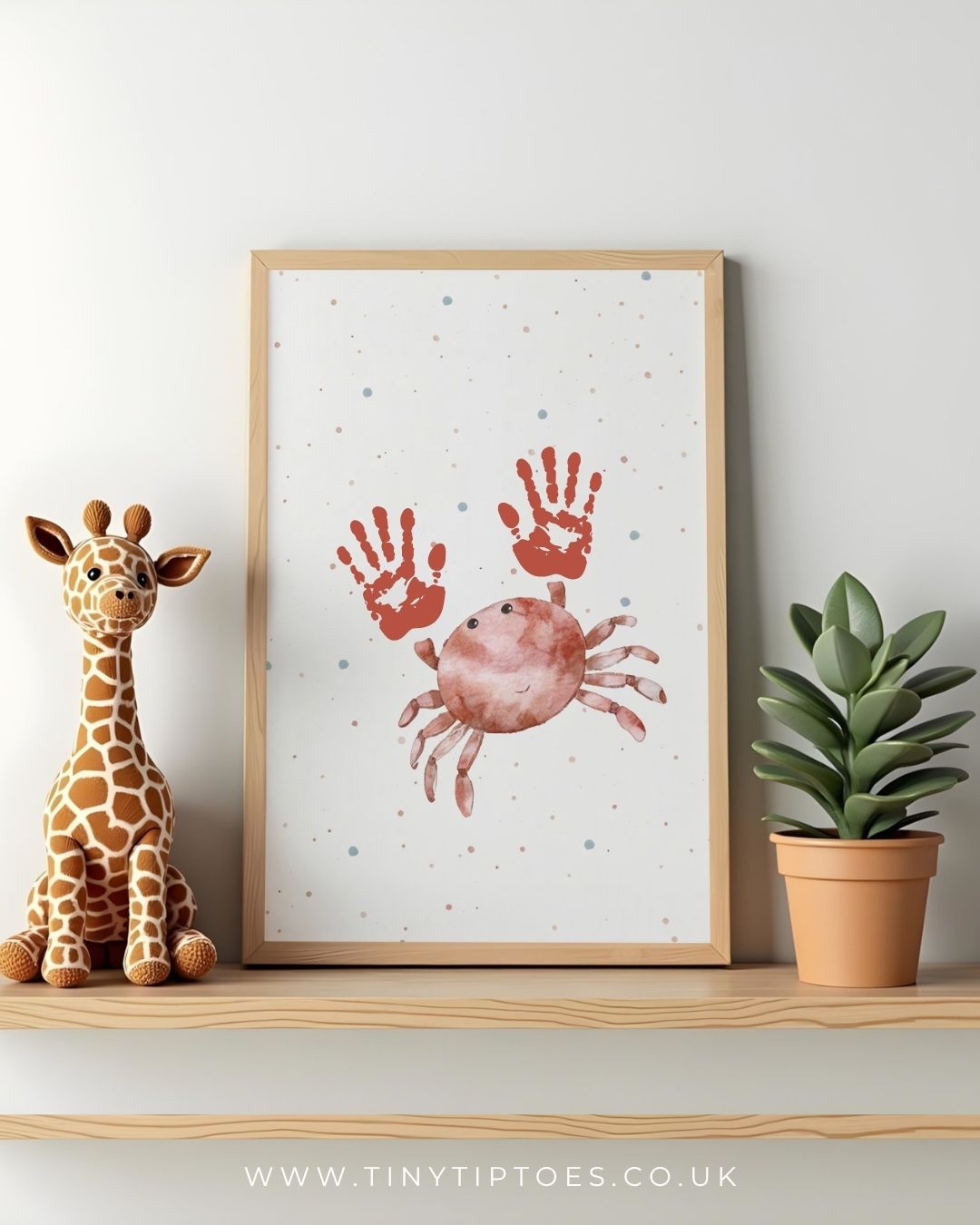 Framed crab artwork with handprints on a shelf with a toy giraffe and plant.