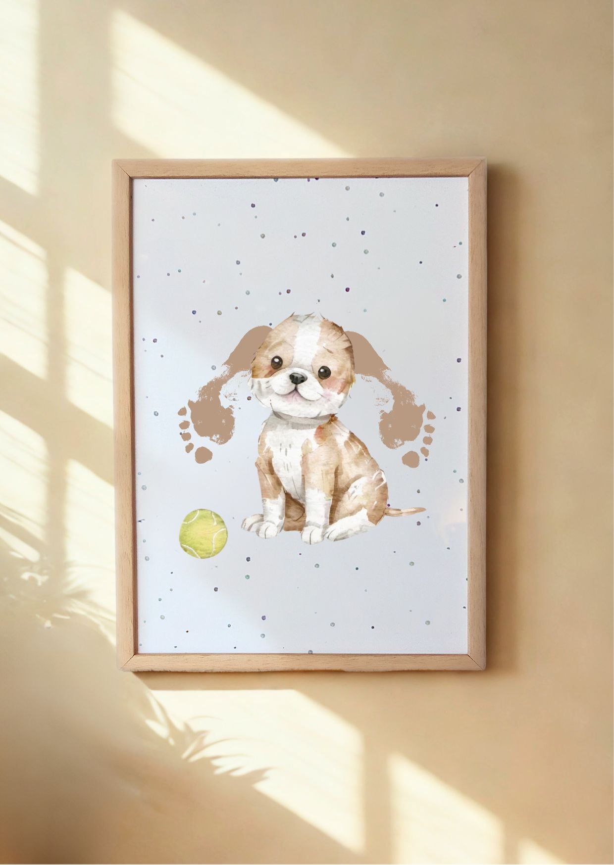 Framed artwork of a puppy with ears made from baby footrpintson a light background, hanging on a wall.