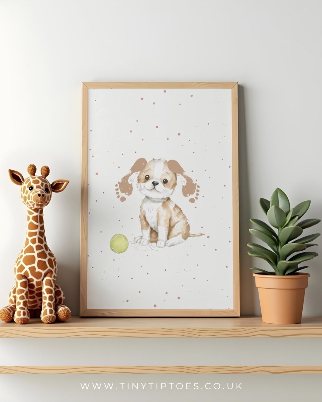 Framed print of a puppy with footprint ears with a toy, sitting on a shelf next to a stuffed giraffe and a potted plant.