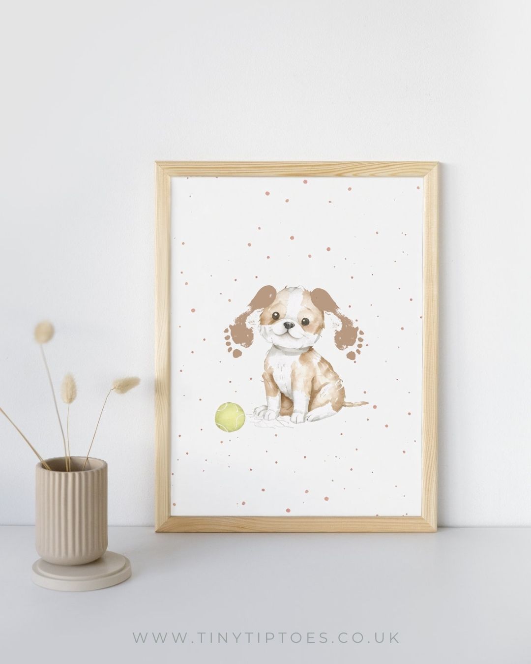 Framed artwork of a dog with footprint ears and a polka dot background on a white wall.