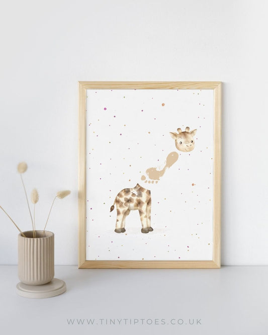 Framed artwork of a giraffe with a footprint neck on a white wall with a vase and dried plants.