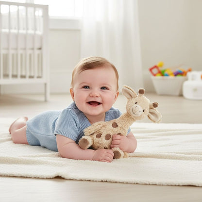 Baby lying on a blanket holding a plush giraffe toy in a bright nursery.