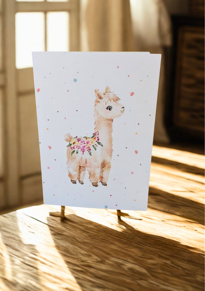 Greetings Card - Watercolour Alpaca. Blank inside. On wooden table with soft sunlight.