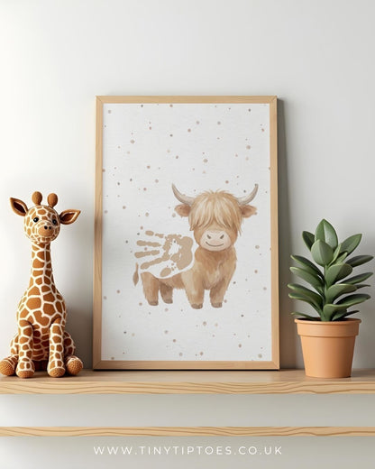 Framed artwork of a highland cow with a handprint body with a toy giraffe and plant on a shelf.