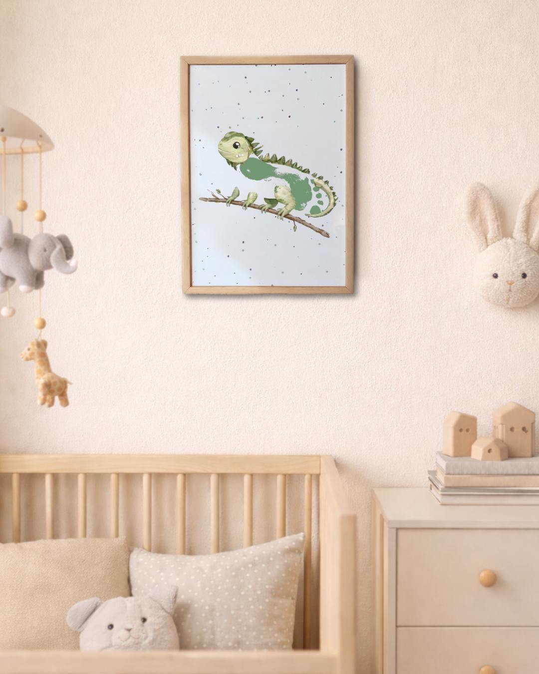 Nursery room with a framed picture of a green iguana with a baby's footprint as the body, cot, and toys.
