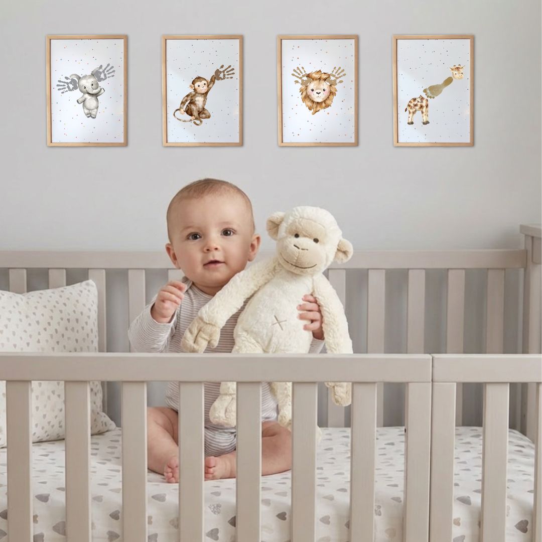 Baby sitting in a crib cot holding a plush toy, with framed animal prints on the wall with baby handprints and footprints