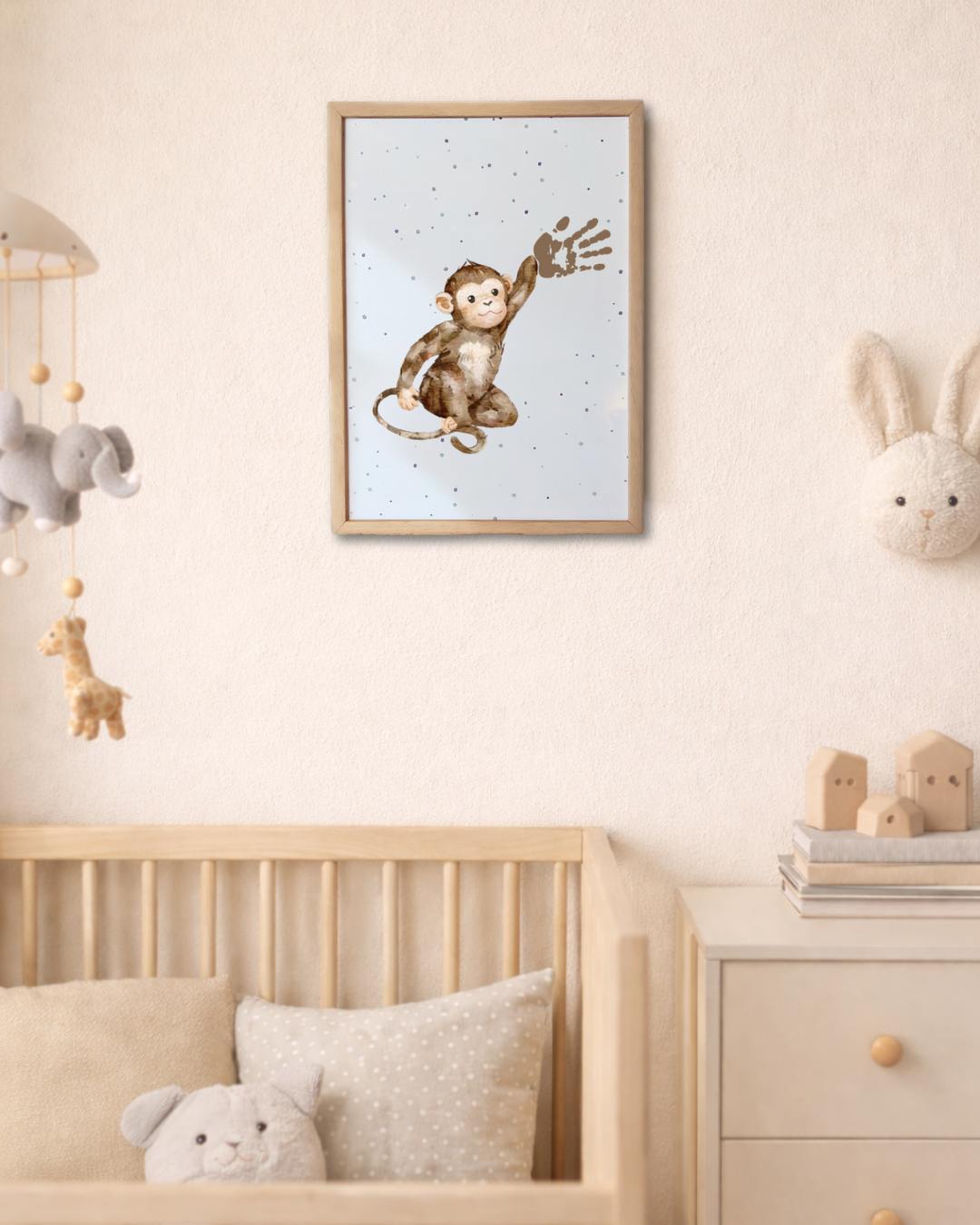 Framed artwork of a monkey on a wall in a nursery with toys and furniture. baby handprint on the monkey