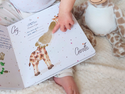 Child's hand holding a book with a giraffe illustration on a soft surface, footprint neck on giraffe