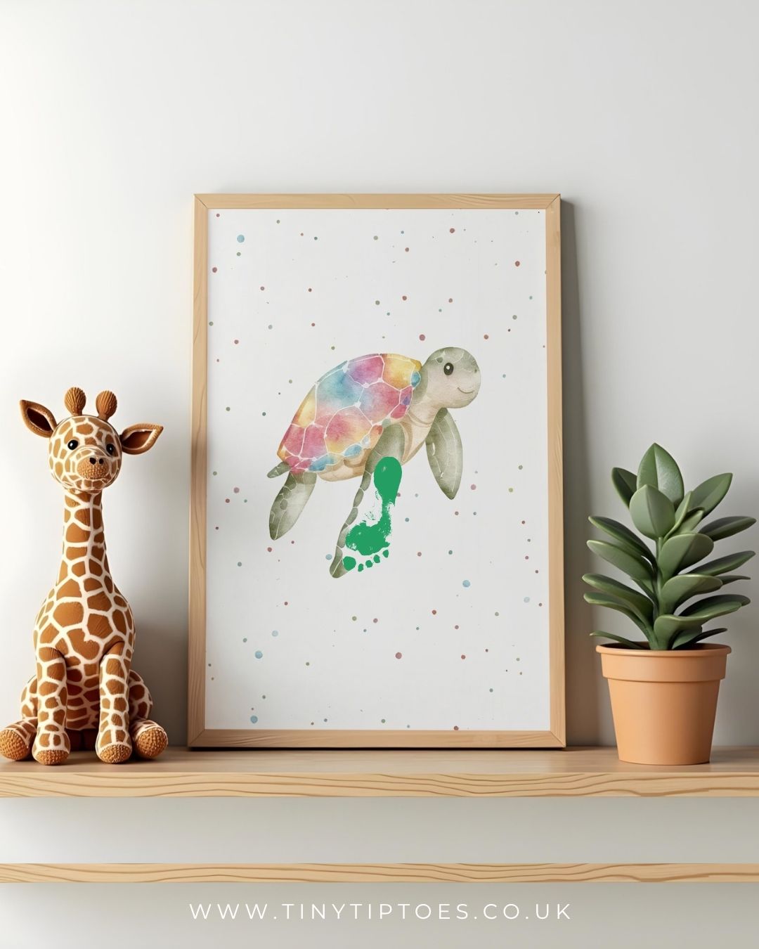 Framed artwork of a colorful turtle footprint on a shelf with a toy giraffe and plant.