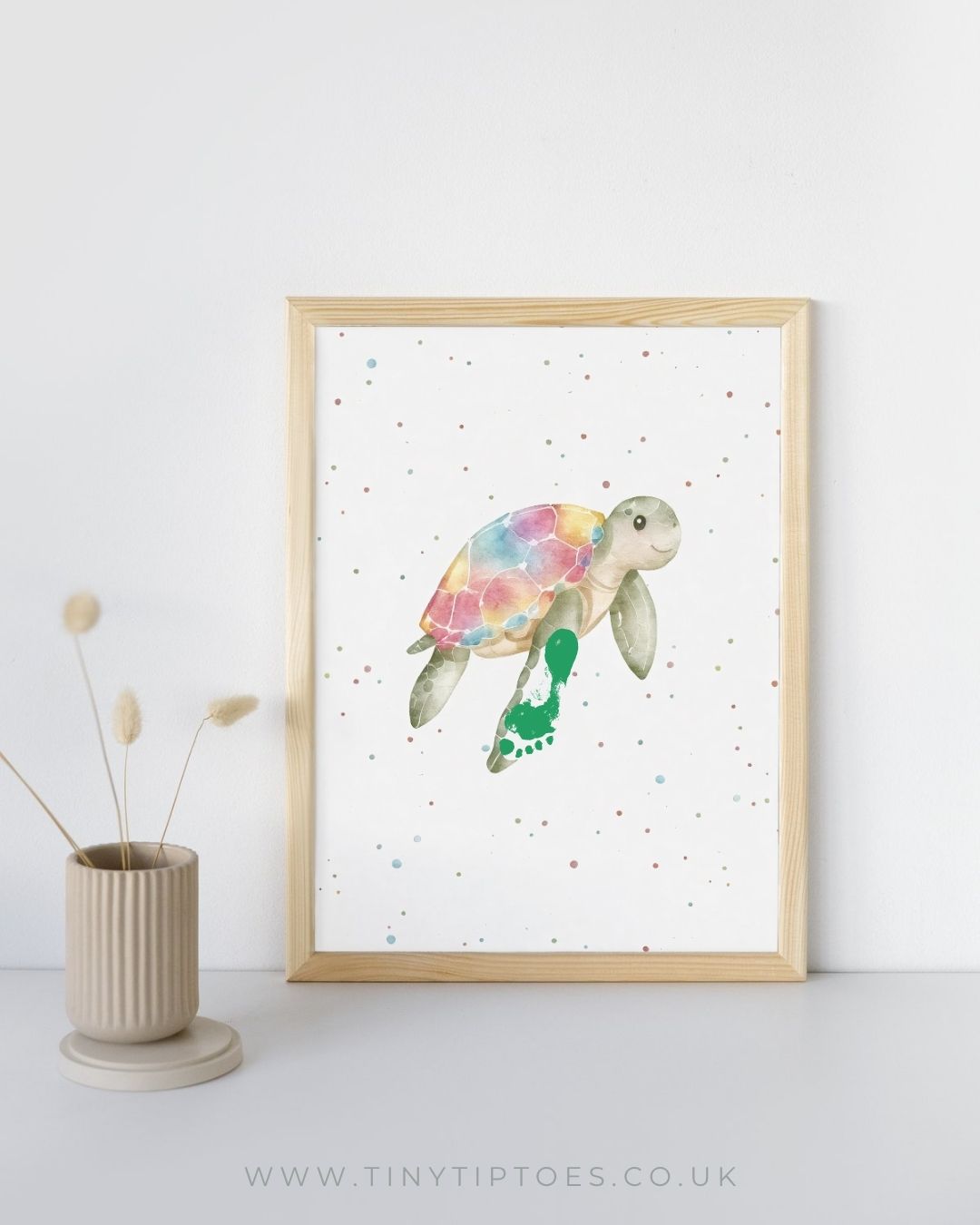 Framed artwork of a colorful turtle with footprint flipper on a white background with a vase and dried plants.