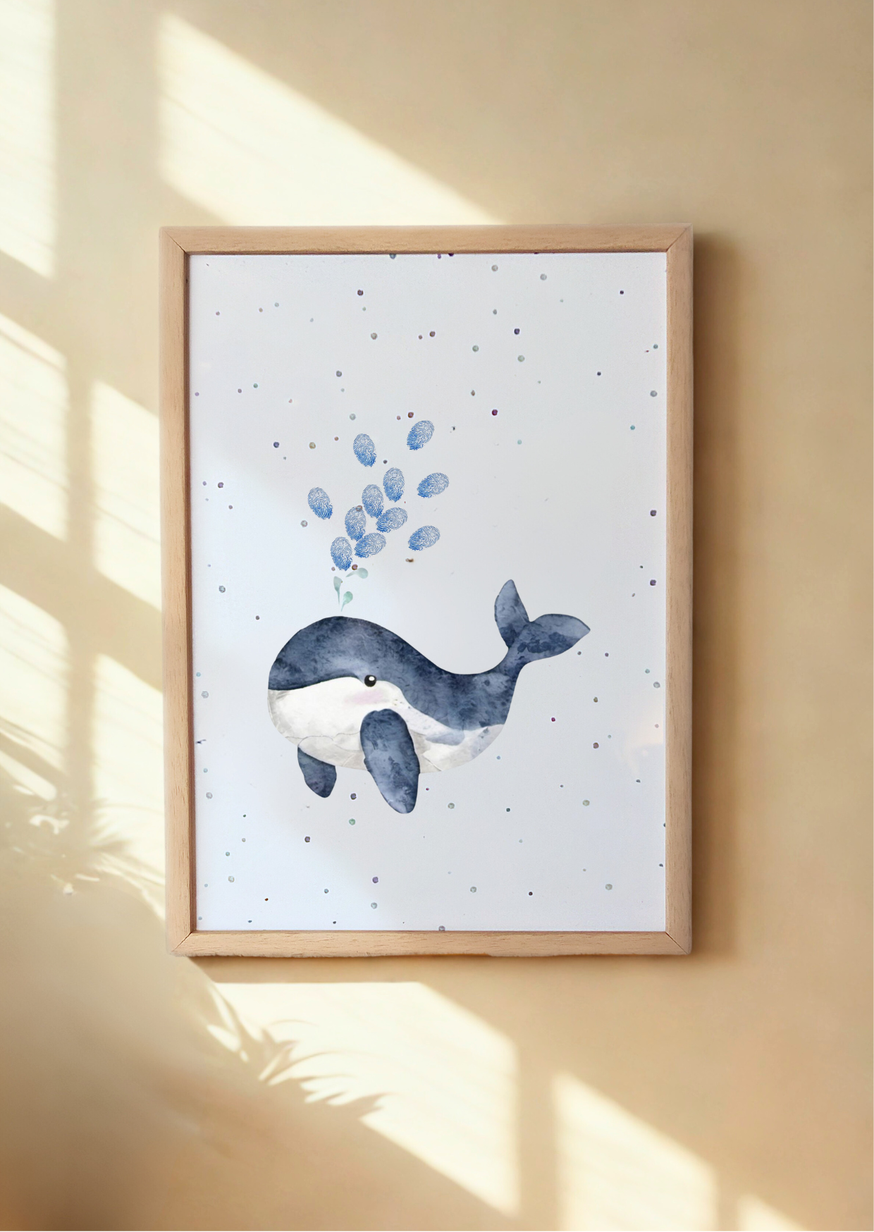 Framed artwork of a whale and fingerprint bubbles on a white background, hanging on a beige wall.