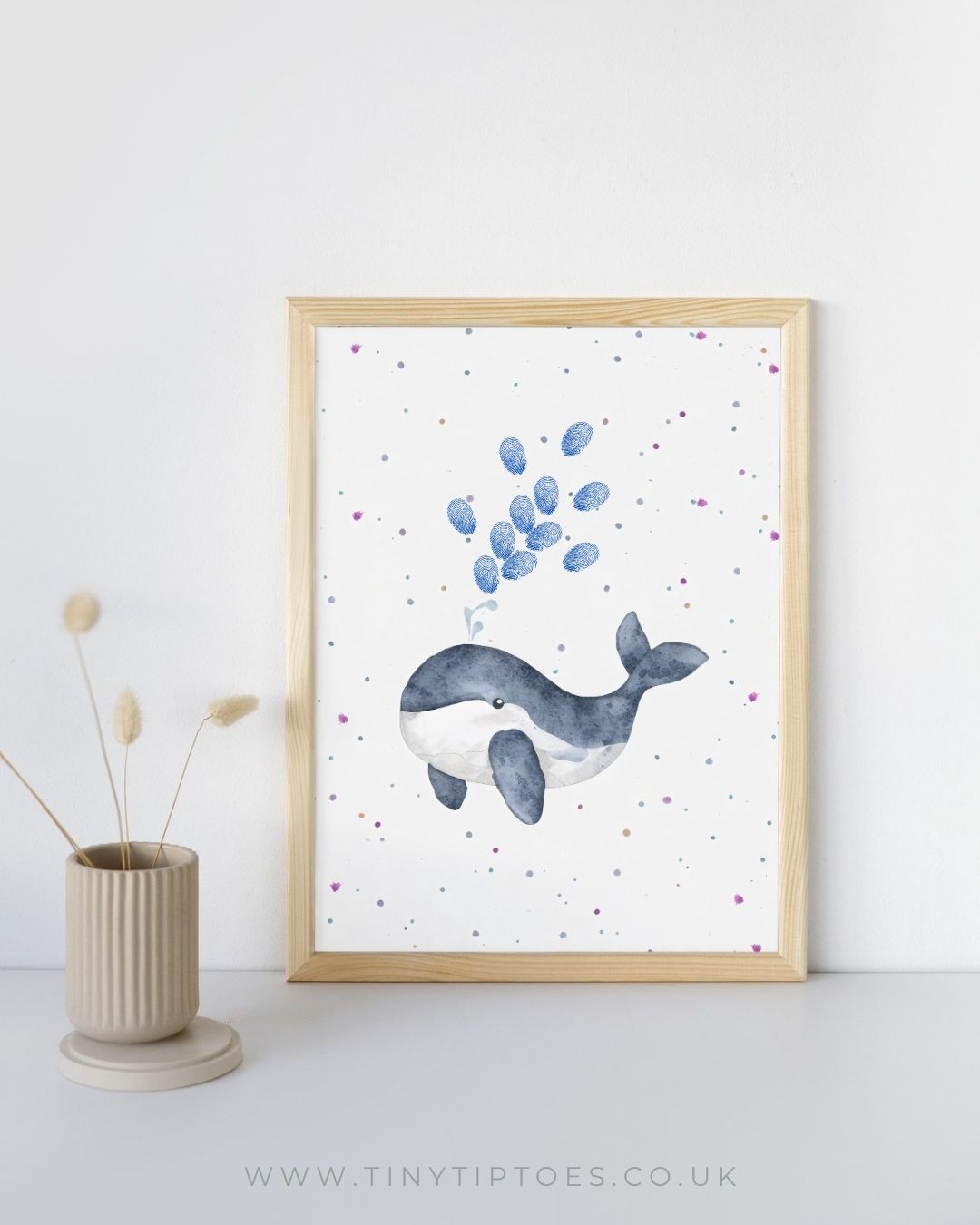 Framed artwork of a whale with fingerprint bubbles on a white background, displayed on a shelf.
