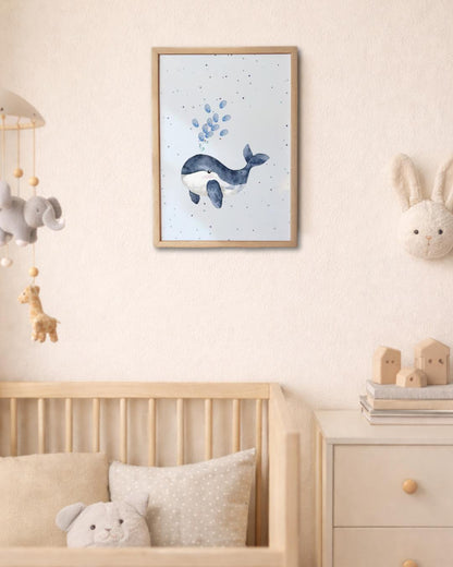 Framed artwork of a whale on a wall in a baby's nursery bedroom with toys and a crib. blue fingerprint bubbles coming from the whale