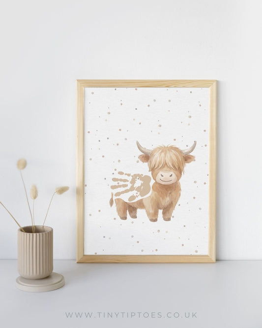 a framed illustration of a highland cow with a handprint body, baby nursery keepsake wall art