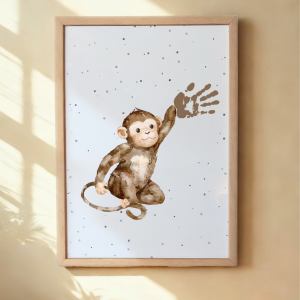 Framed artwork of a monkey on a white background with a wooden frame, hanging on a beige wall. Framed Monkey Handprint Keepsake Print with child's handprint as its hand