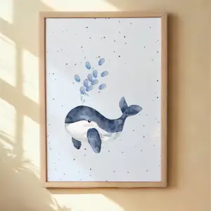 Framed artwork of a whale and bubbles on a white background, hanging on a beige wall. Framed Whale print with child's fingerprints as water