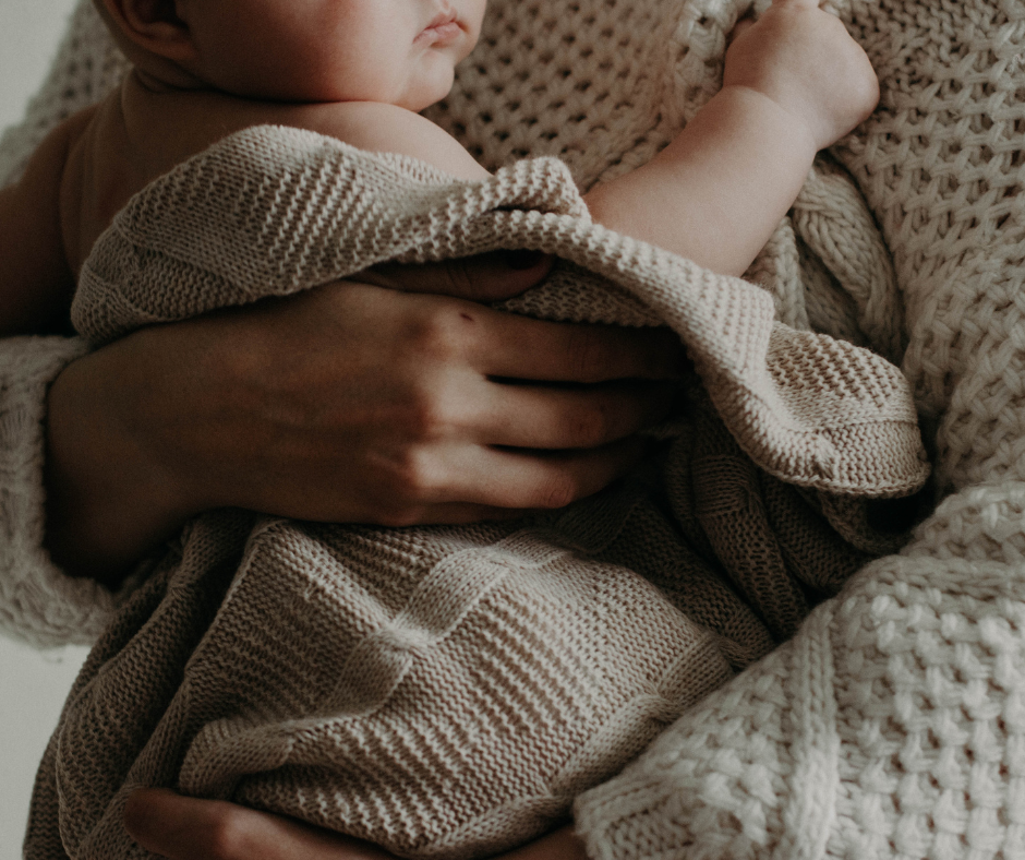 Parent holding newborn baby wrapped swaddled in soft blanket – intimate bonding moment and newborn keepsake memory concept