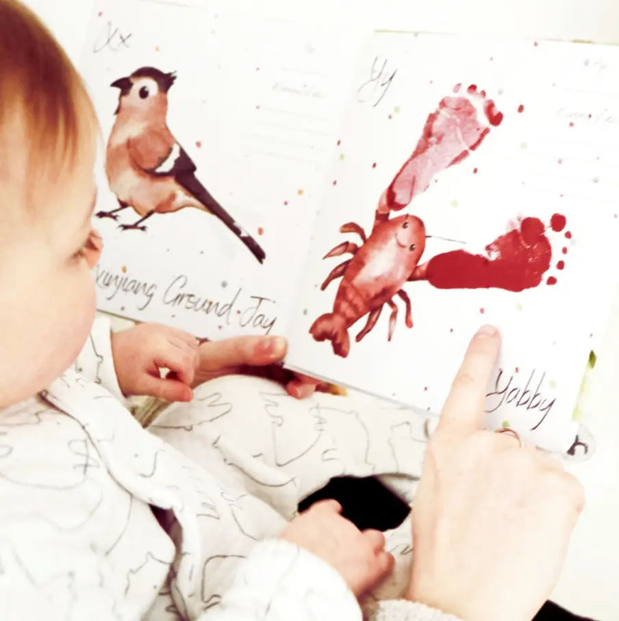 baby and mum looking at baby's handprint in their keepsake book